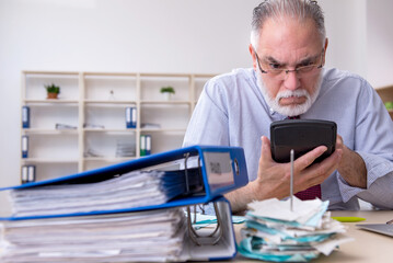 Old male accountant in budget planning concept in the office