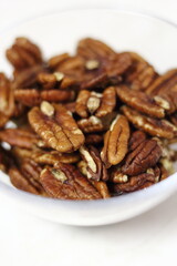 Pecan halves in glass bowl. Isolated on white background.