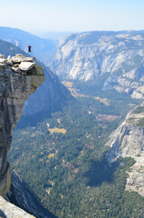 Vertical shot of a person jumping on a cliff at Half Dome, Yosemite, California