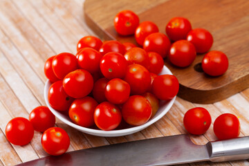 Small red cherry tomatoes on wooden background, food preparation