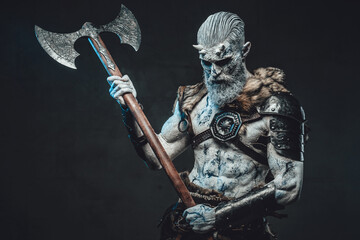 Bringer of the death king with pale skin holding two handed axe and looking down in dark background.