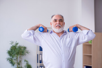 Aged male employee doing physical exercises during break