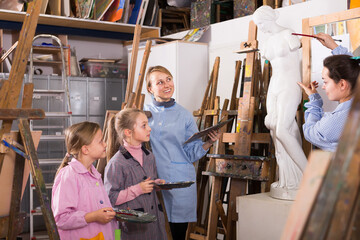 Young teacher explains how to draw female students in an art studio