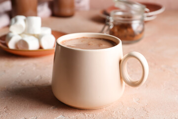 Cup of hot cacao drink on color background