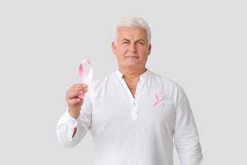 Mature man with pink ribbon on light background. Breast cancer awareness concept