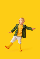 Surprised little boy in autumn clothes on color background