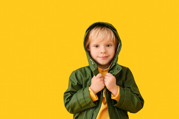 Cute little boy in autumn clothes on color background