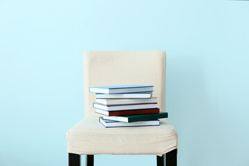 Stack of books on chair near color wall