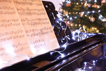 Grand piano with note sheets and Christmas decor, closeup