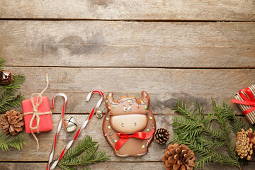 Tasty cookie in shape of bull and Christmas decor on wooden background
