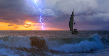 Sailing yacht in a stormy weather with thunder and lightning at sunset