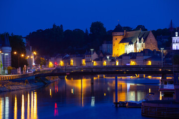 Obraz premium Scenic view of lighted ancient Laval castle on banks of Mayenne river at summer dusk, France