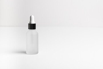 Face serum in a white glass package, bottle on a white neutral background. Natural treatment for dry skin with oils, vitamins and collagen. Packaging of cosmetic beauty product, pack shot, copy space
