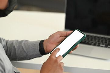 Cropped shot of man office worker holding smartphone while working in office room.