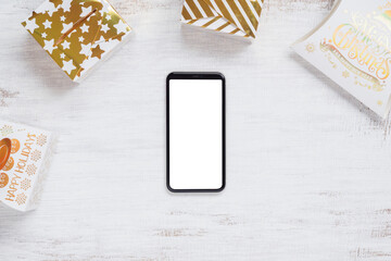 Mockup blank white screen smartphone on white wood background for Christmas and New Year party background, Flat lay top view with copy space for your Merry Christmas and Happy New year artwork.