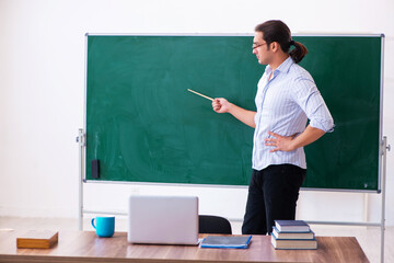 Young male teacher in front of blackboard