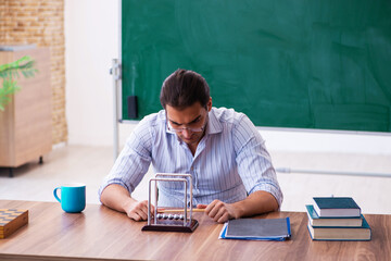 Young male teacher physicist in front of blackboard