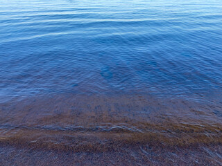 Texture of the clean lake water background, evening beach
