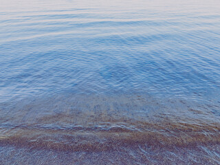 Texture of the clean lake water background, evening beach