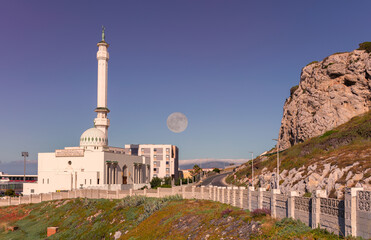 The White Mosque on the British Territory of Gibraltar in the early morning. The full moon over the Spanish mountains illuminates the scene. It will go under soon.