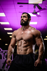 Fototapeta na wymiar bodybuilding motivation of strong young bearded male in sport gym lit with purple light