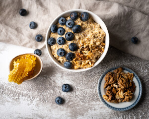 Healthy breakfast bowl: oatmeal with blueberries, nuts and honeycomb piece. Oat flakes with berries.