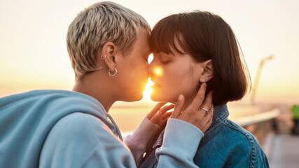 Two women kissing outdoors, Young lesbian couple enjoying romantic moments together at sunrise