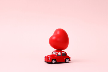 Small red retro toy car with heart on the roof. New Year, Christmas, Valentines Day, World Womans Day.