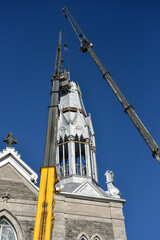 Fototapeta na wymiar Repair of the steeple of the church of Saint-Pie in Quebec with two cranes