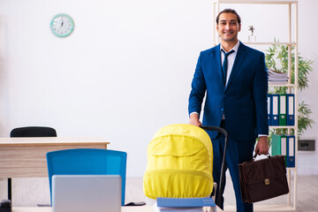 Young male employee looking after kid at workplace
