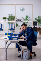 Young businessman employee rejecting new ideas with lots of pape