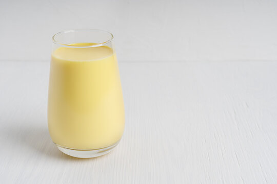 Ayurvedic Indian golden turmeric milk or haldi doodh which is source of antioxidants and anti-inflammatory compounds served in drinking glass on white wooden background. Image with copy space