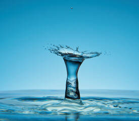 Water drop falling down. Abstract blue background.