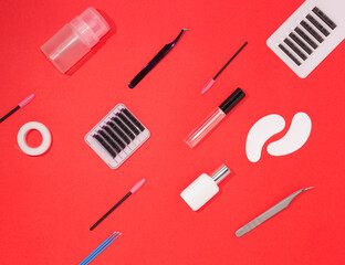 Tools for eyelash extension on an orange background, top view. Artificial eyelashes, tweezers, microbrushes, patches and brushes for lashmaker.