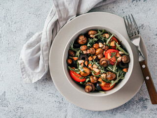 Salad with arugula, mini champignons, cherry tomatoes, black olives, pine nuts. Vegetarian salad top view or flat lay. Copy space. Horizontal