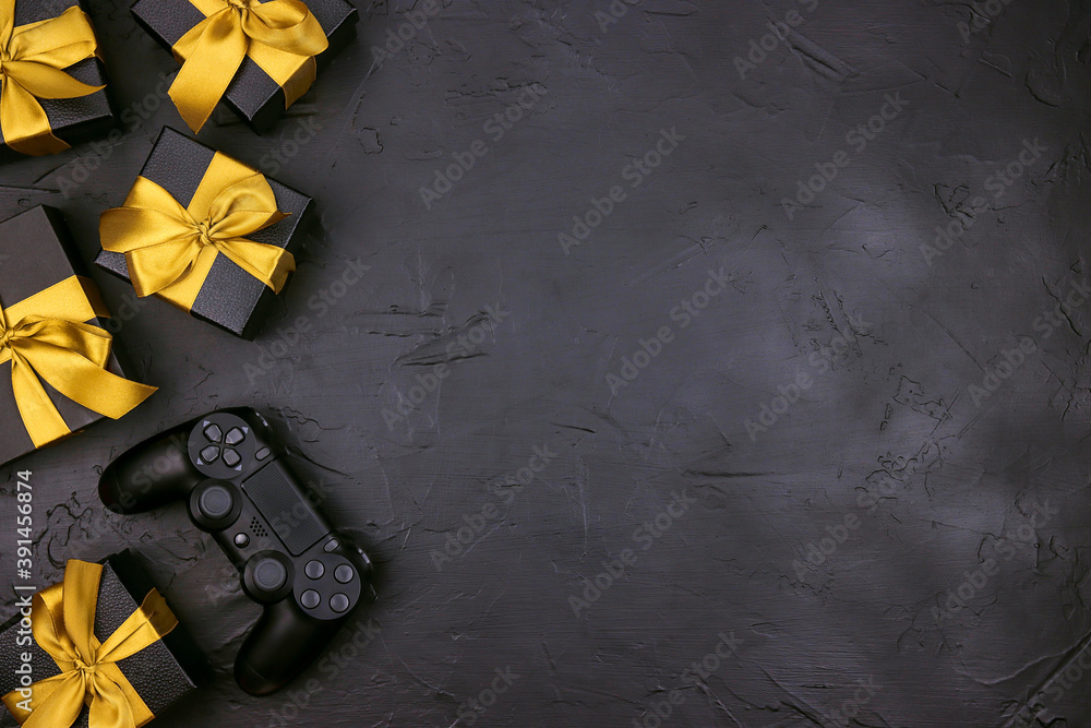 Wall mural Black background with joystick gaming controller and gift boxes with gold ribbon.