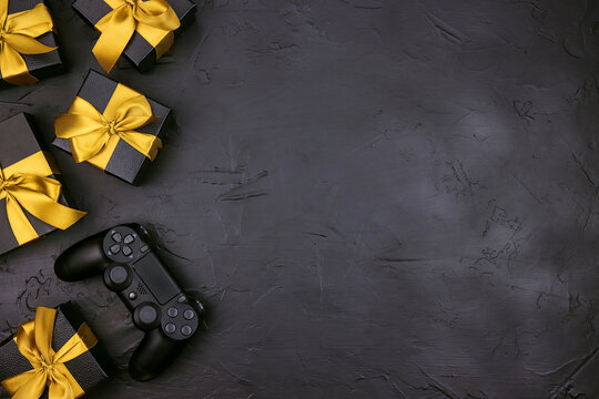 Black background with joystick gaming controller and gift boxes with gold ribbon.