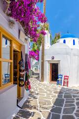 Traditional Cycladitic alley with narrow street, whitewashed houses and a blooming bougainvillea flowers in Naousa  Paros island, Greece