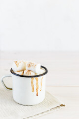 Hot chocolate with marshmallows and cinnamon in a white mug with drips.