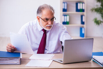 Fototapeta premium Old male employee working in the office