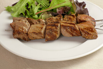 brochettes de boeuf grillées et salade dans une assiette