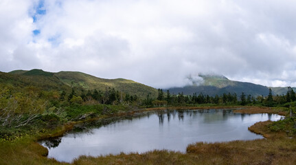 Fototapeta na wymiar View of one of four marsh lakes around Lake Rausu with mountains reflected in lake