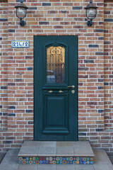 Front dark green wooden door on the red brick house
