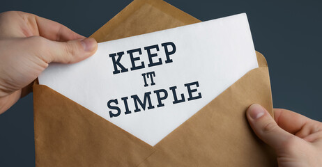 Male hands holding craft envelope with text KEEP IT SIMPLE on blue background