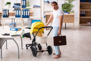 Young male employee looking after newborn at workplace