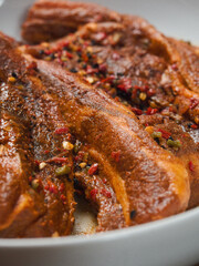 Raw pork belly slices in Korean style marinade on a white plate. Meat industry product