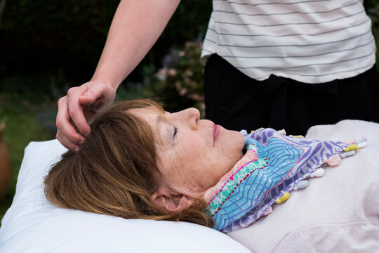 Reiki therapist with a client in a therapy session touching meridian points on the body.