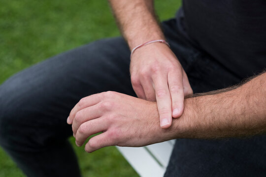 A man seated, two fingers on his opposite wrist, EFT touching therapy