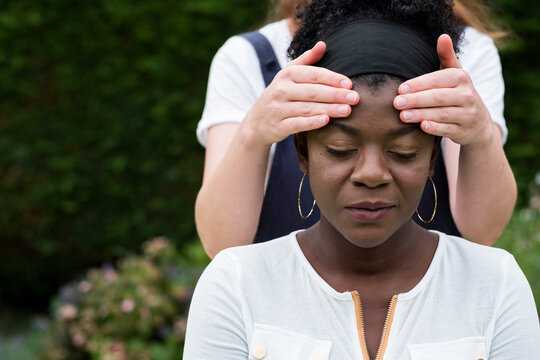 Therapist with her hands on a client's temples, outdoor therapy session