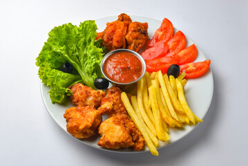 Deep fried chicken platter, chicken wings, nuggets, french fries and fresh green salad with dip tomato sauce.
